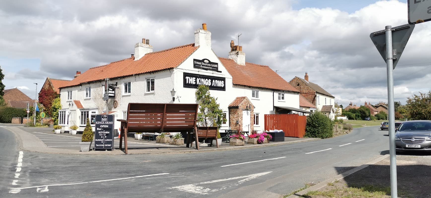 The Kings Arms pub in Sandhutton, Yorkshire, with a white exterior, red roof, and outdoor seating area.