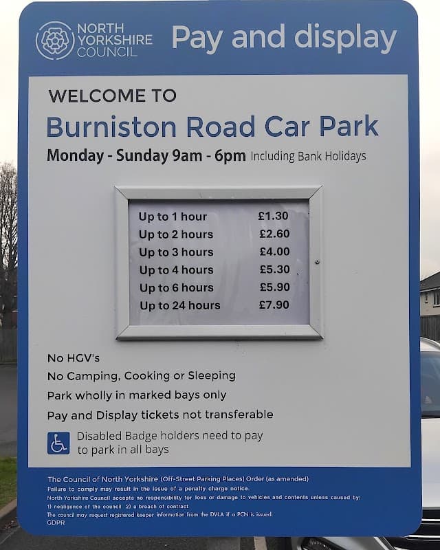 Sign for Burniston Road Car Park listing parking fees and regulations, with a blue background and clear text.