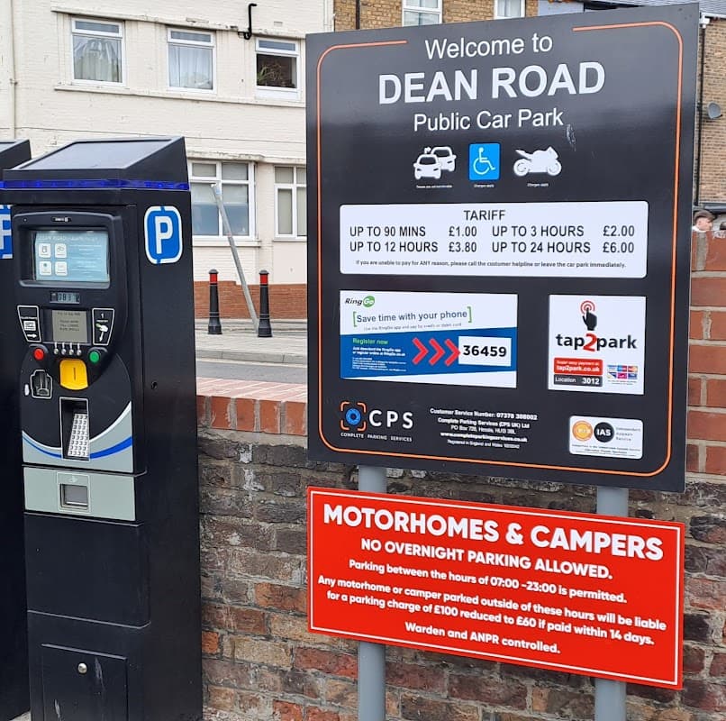 Signage for Dean Road Public Car Park with parking machine and information on tariffs and restrictions.