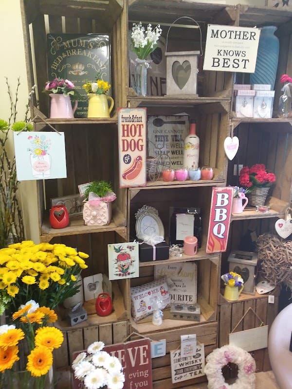 Colorful floral arrangements and decorative signs displayed on wooden crates, showcasing a charming floral shop atmosphere.