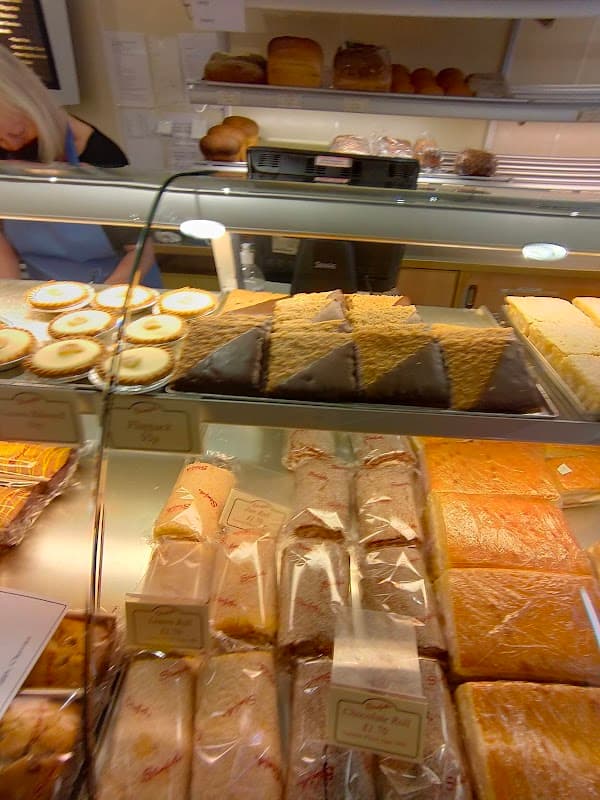 Display case filled with various baked goods, including cakes, pastries, and loaves of bread at Staniforths Ltd.