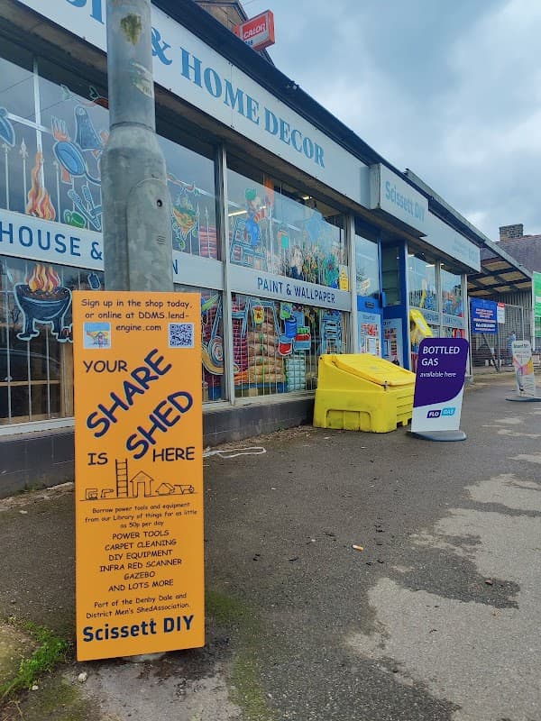 Colorful storefront of Scissett DIY featuring paint and wallpaper, with signs for services and products outside.