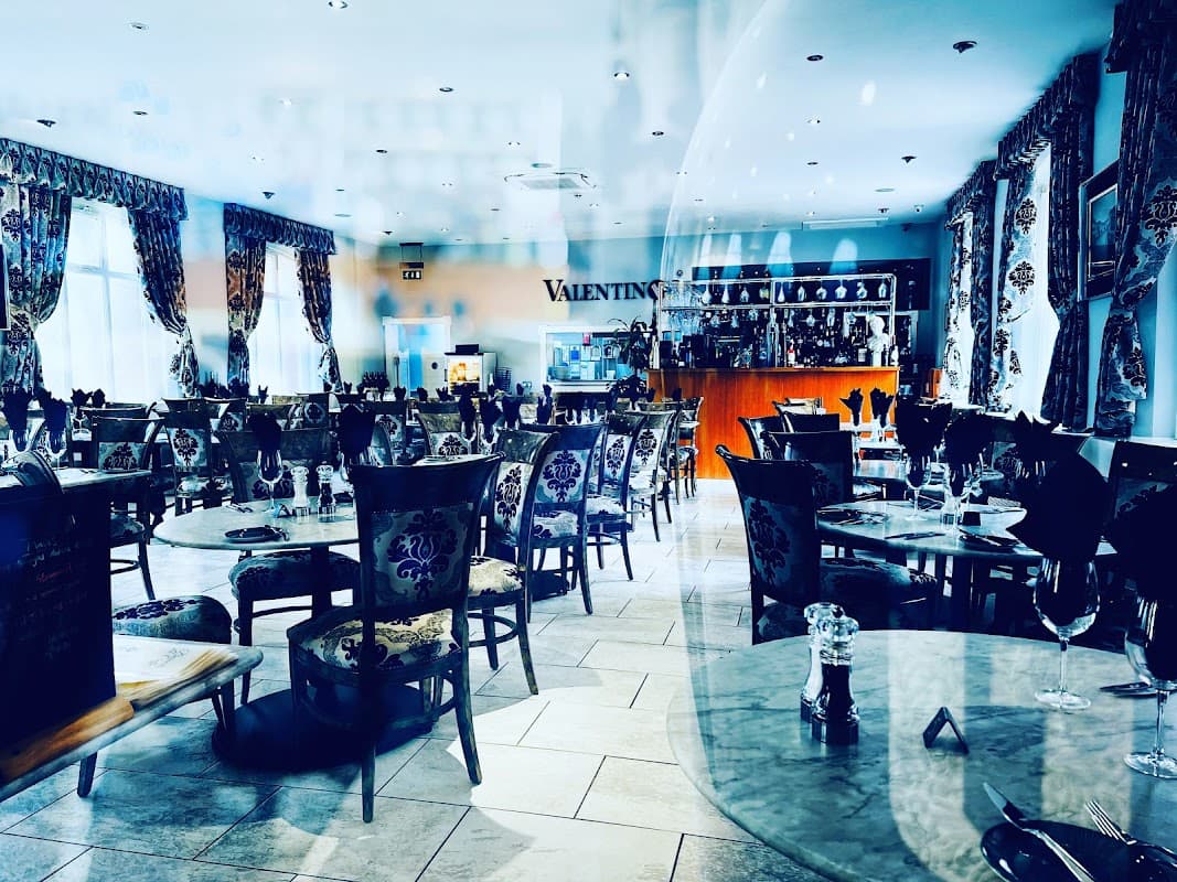 Elegant restaurant interior with ornate chairs, tables set for dining, and decorative curtains in a bright, inviting space.