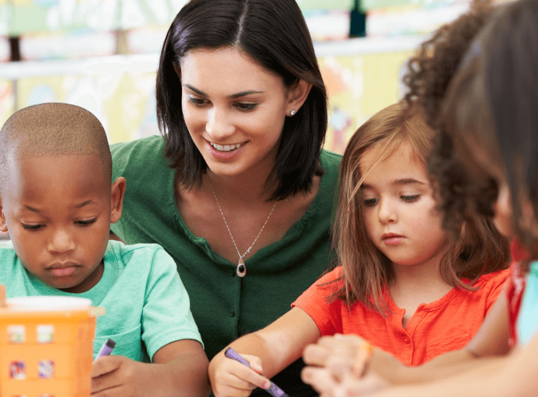 Children engaged in art activities with a smiling teacher, surrounded by colorful craft supplies.