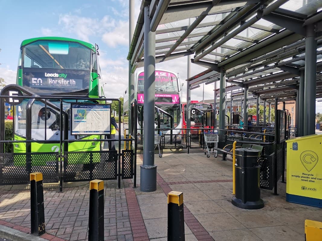 Seacroft bus station featuring multiple buses, waiting areas, and recycling bins under a covered structure.