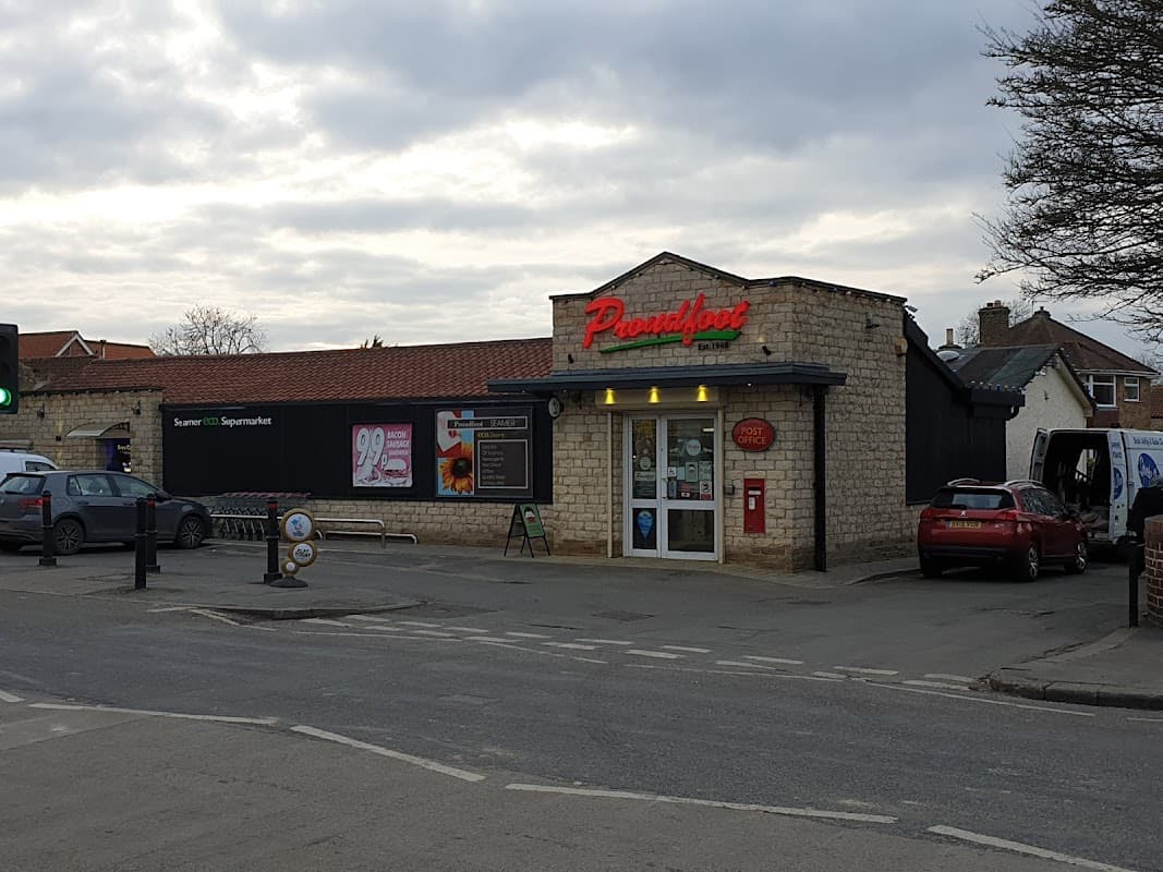 Proudfoot shop in Seamer, Scarborough, featuring a stone facade, parking area, and nearby vehicles.