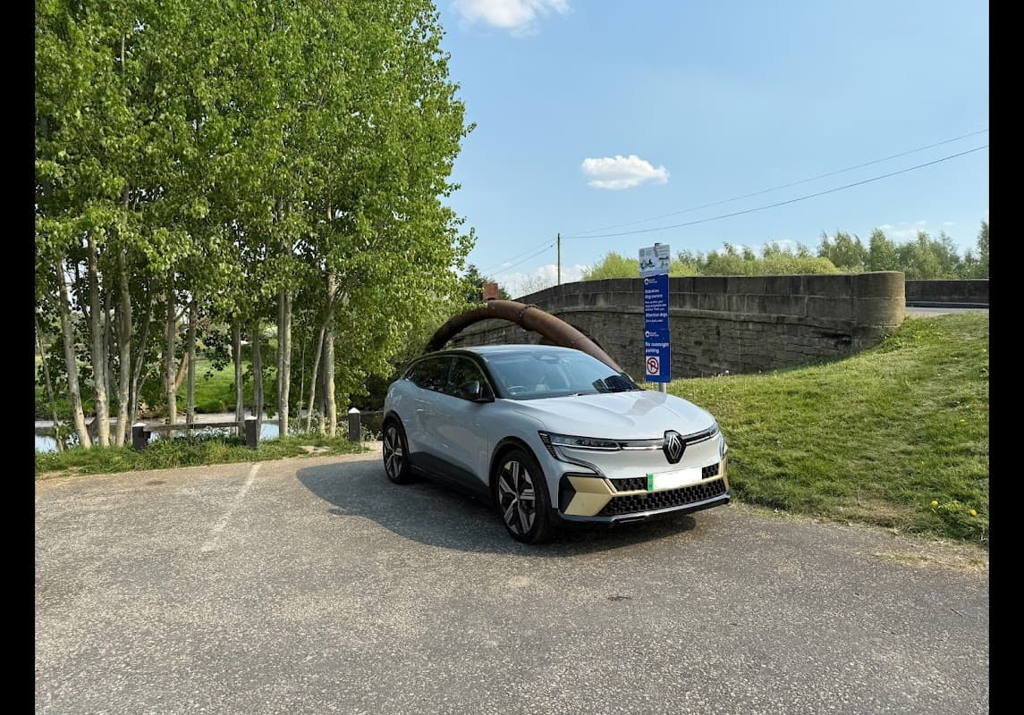 A silver car parked near trees and a stone wall under a clear blue sky in Selby, Yorkshire.