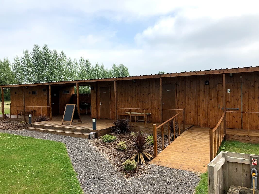 Wooden cabins with a deck, surrounded by greenery and gravel pathways at The Oaks Lakes Caravan Park in Sessay, Yorkshire.