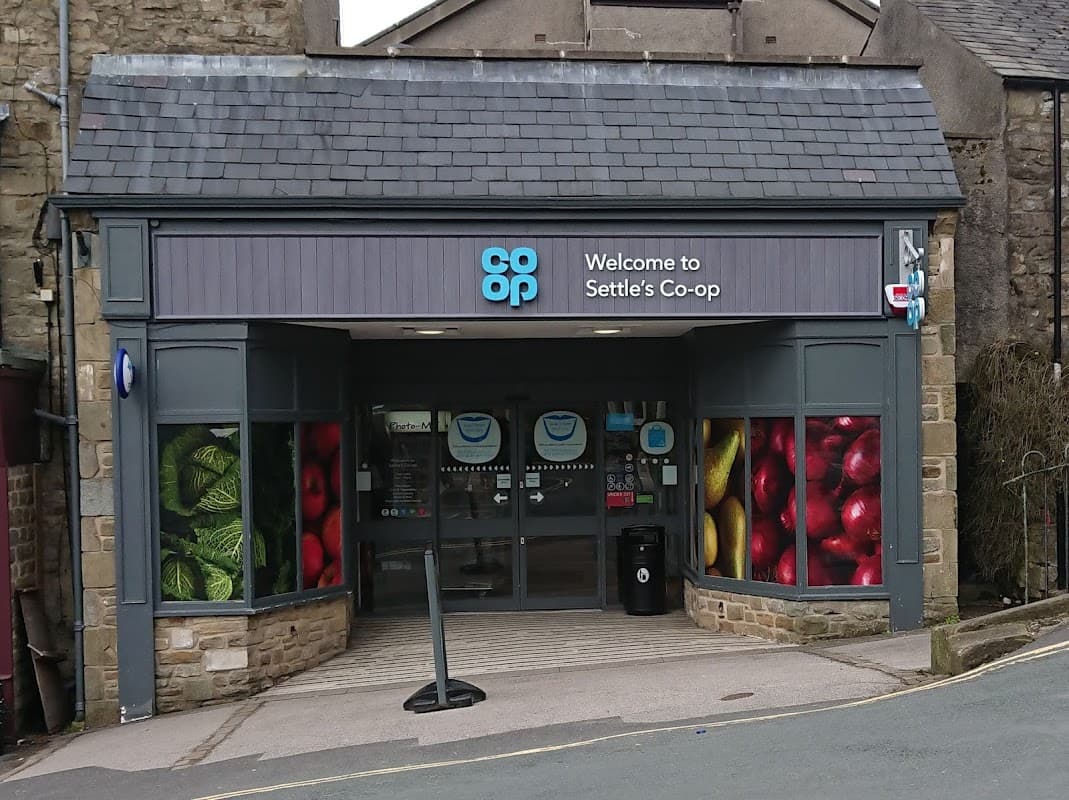 Entrance to Settle Co-op with colorful fruit and vegetable displays on windows, located in Market Square, Yorkshire.