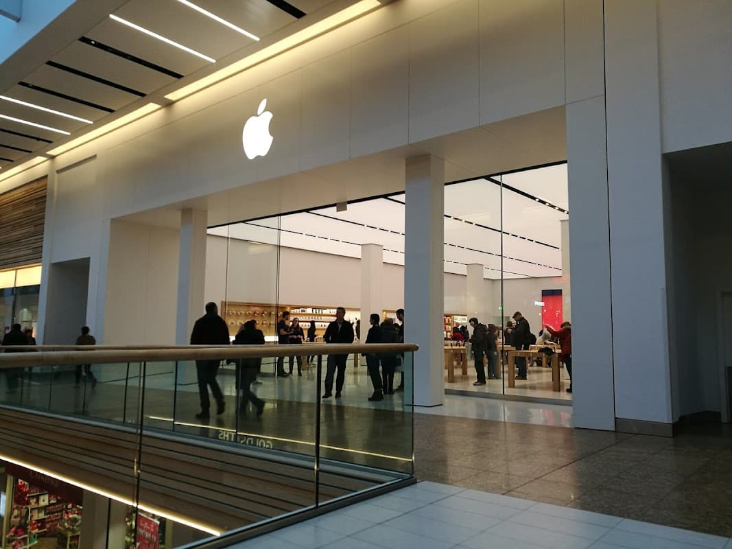 Apple store entrance in Meadowhall, featuring a large logo and a modern, spacious interior with customers browsing.