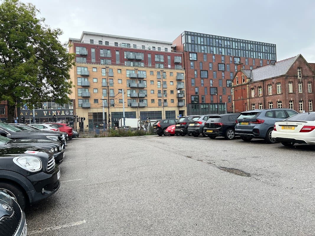 Carver Lane Car Park with parked cars, modern buildings, and a historic brick structure in Sheffield.