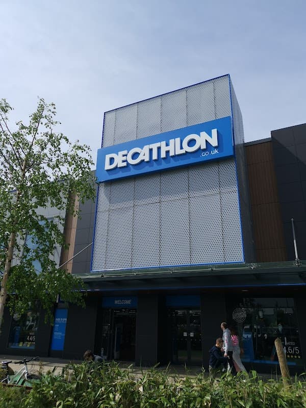 Decathlon store exterior in Sheffield with large blue signage and modern architectural design. Green plants in foreground.