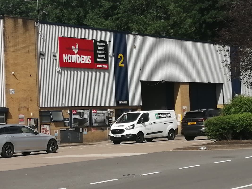 Howdens store exterior in Hillsborough, Sheffield, featuring a sign, delivery van, and parked cars.