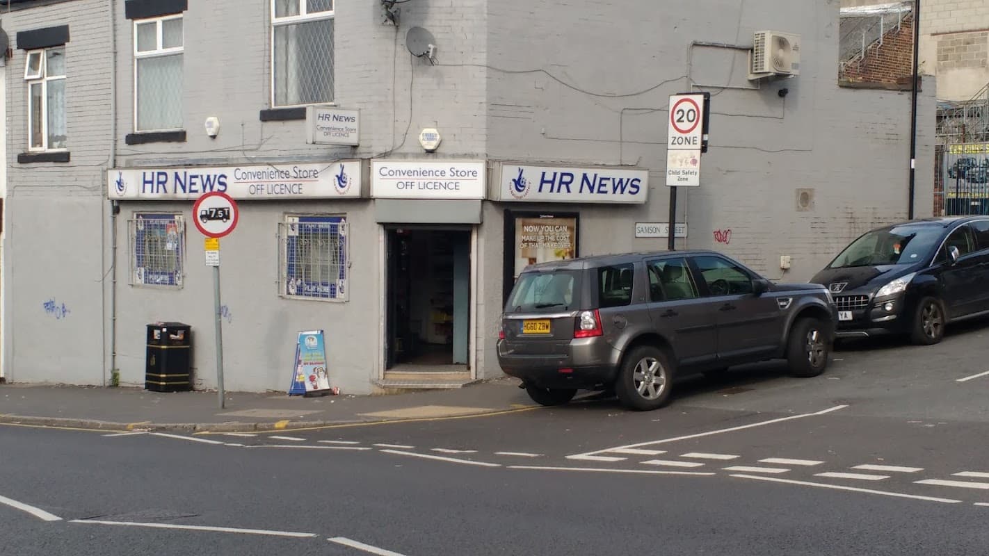 Corner shop with "HR News" sign, parked cars, and nearby traffic signs in a Sheffield neighborhood.