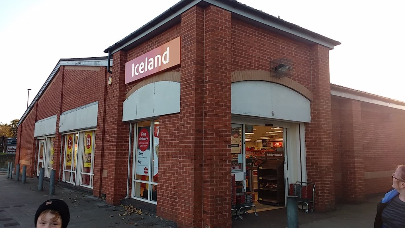 Red brick supermarket with "Iceland" sign, shopping carts outside, and people nearby in Sheffield, Yorkshire.