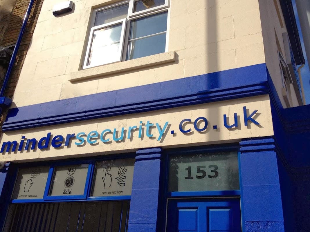 Signage for Minder Security & Fire, featuring blue and white colors, with website and services listed.
