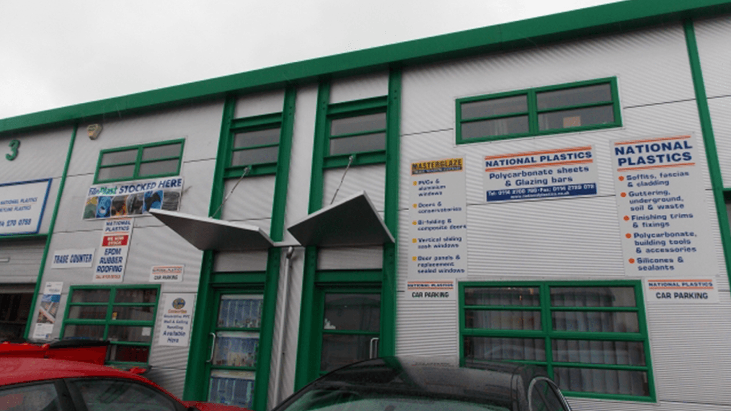 Exterior of National Plastics in Sheffield, featuring signage for products and services, with red cars parked in front.