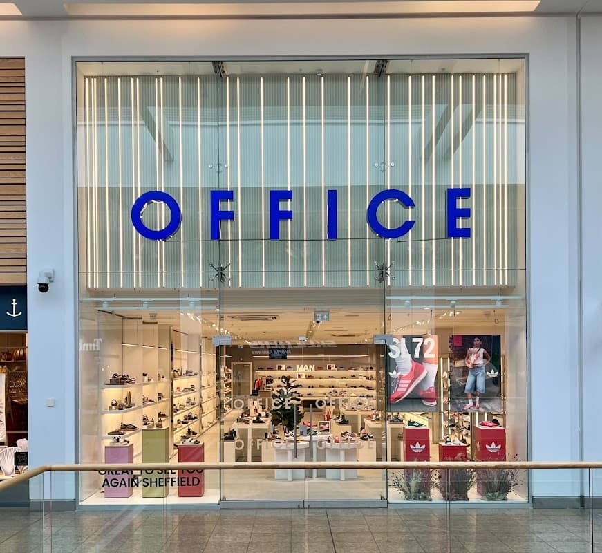 Bright storefront of OFFICE Meadowhall, showcasing various shoes with vibrant signage and displays inside.