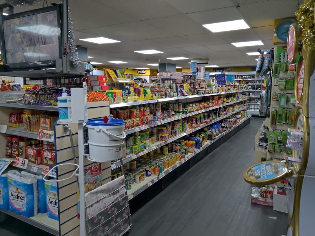 Aisles of shelves stocked with various groceries and snacks in a well-lit convenience store.