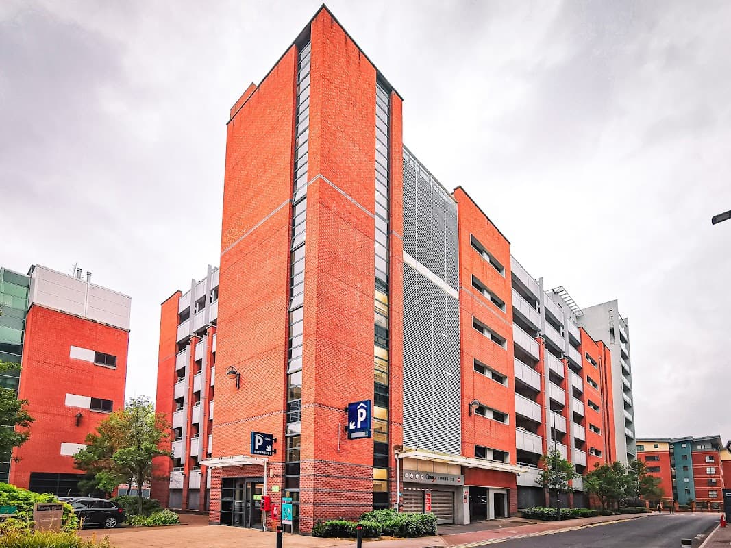Modern multi-story car park with red brick exterior, large windows, and parking signage in Sheffield, Yorkshire.