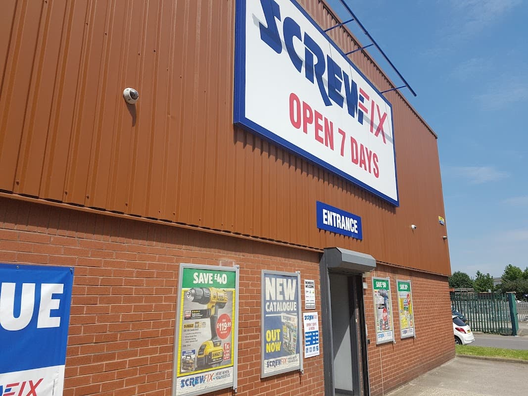 Screwfix Sheffield storefront with a large sign, entrance door, and promotional posters on a sunny day.