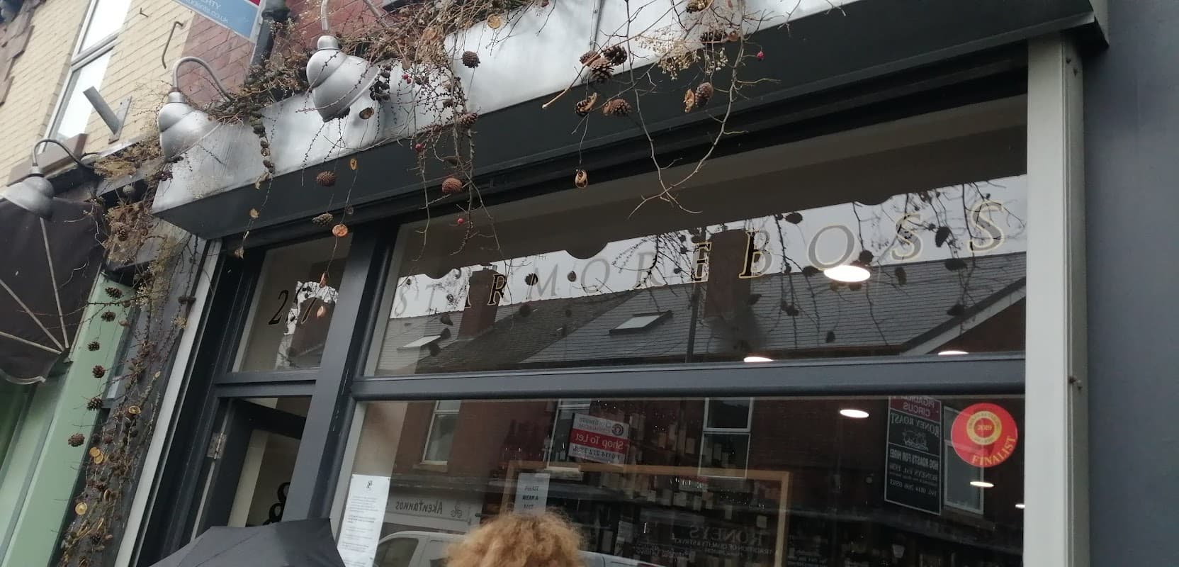 "StarmoreBoss Off Licences storefront with large glass windows and decorative vines, located in Sheffield, Yorkshire."
