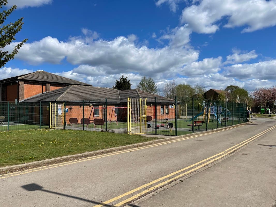 Eversley Park Centre with playground equipment, green space, and blue sky dotted with clouds in Sherburn in Elmet.