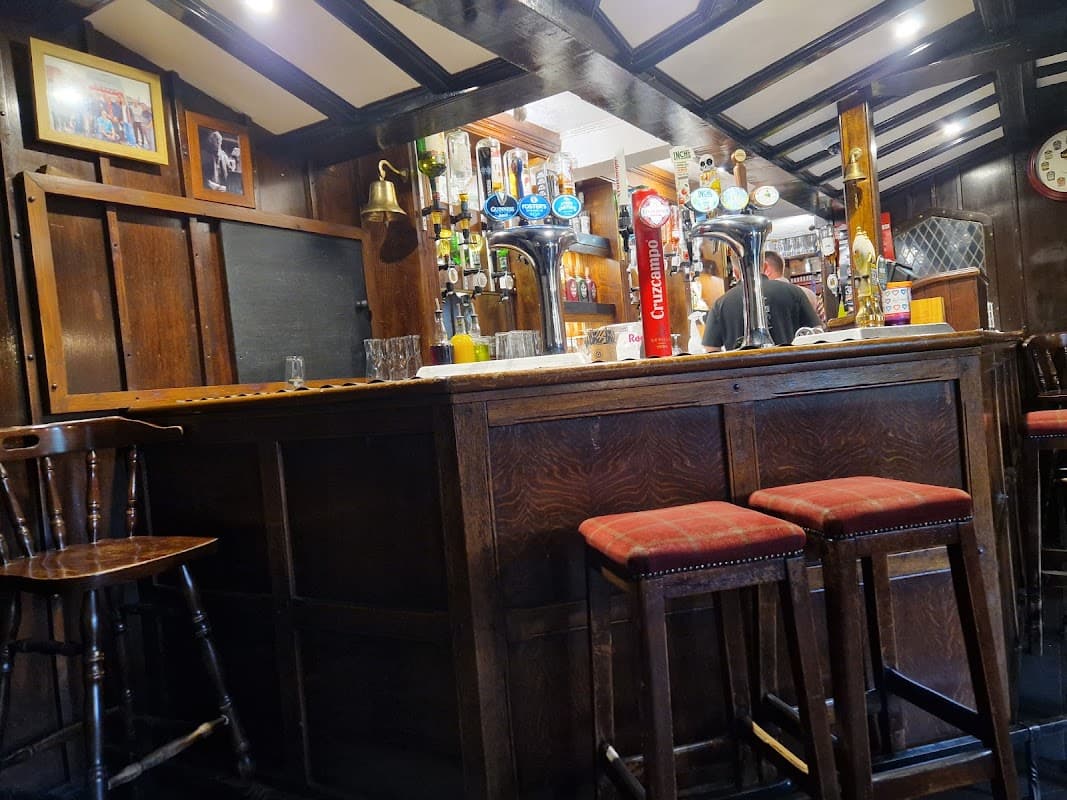 Cozy bar interior with wooden furnishings, beer taps, and a bartender in the background at Highwayman Inn, Sheriff Hutton.