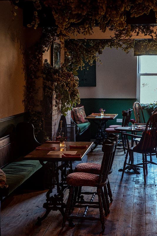 Cozy bar interior with wooden tables, chairs, and floral decorations, creating a warm, inviting atmosphere.