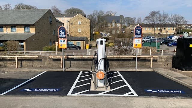 Osprey Charging Station with two charging points, surrounded by buildings and parked cars in Skipton, Yorkshire.