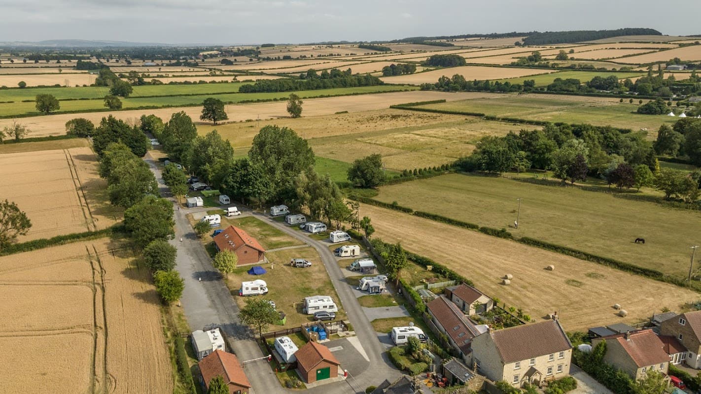 Aerial view of Slingsby Camping site with caravans, green fields, and distant hills in Yorkshire.