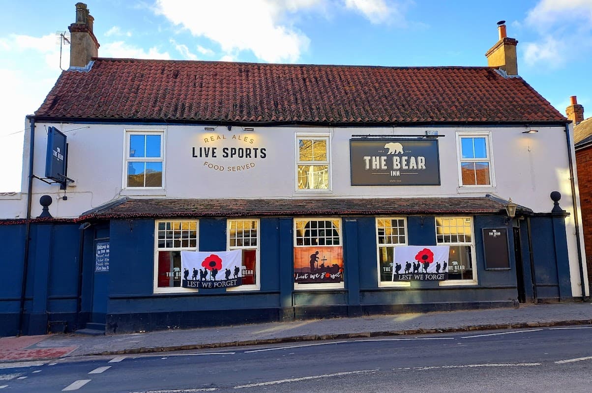 The Bear Inn features a blue facade, poppy tributes, and signs for real ales and live sports in South Cave, Yorkshire.