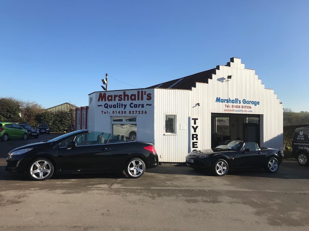 Marshalls Quality Cars dealership with two black cars parked outside and a white building featuring signage and contact info.