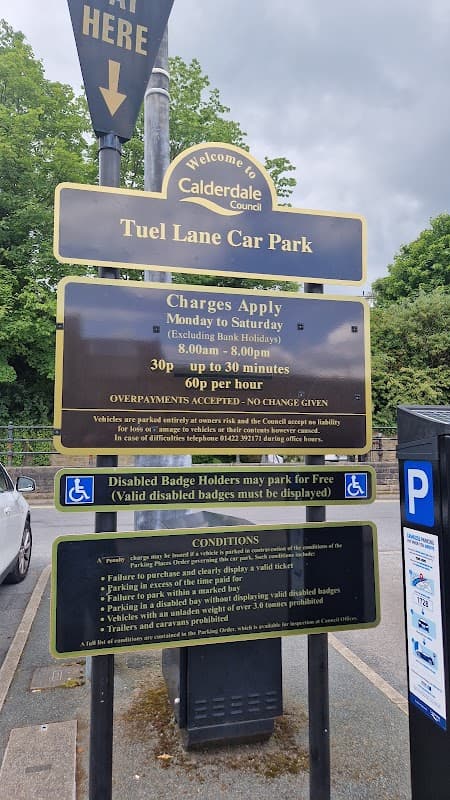 Welcome sign for Tuel Lane Car Park with parking charges and conditions displayed, surrounded by greenery.