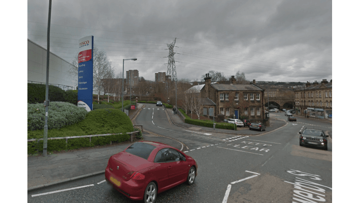 Pay & Display parking sign for YourParkingSpace; red car on the road, buildings and power lines in the background.