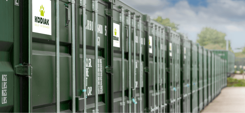 Green storage containers lined up with "KODIAK SELF STORAGE" signage in Sowerby, North Yorkshire under a cloudy sky.