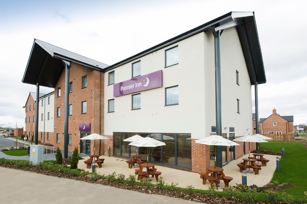 Premier Inn Thirsk hotel featuring a modern exterior, outdoor seating with umbrellas, and landscaped surroundings.