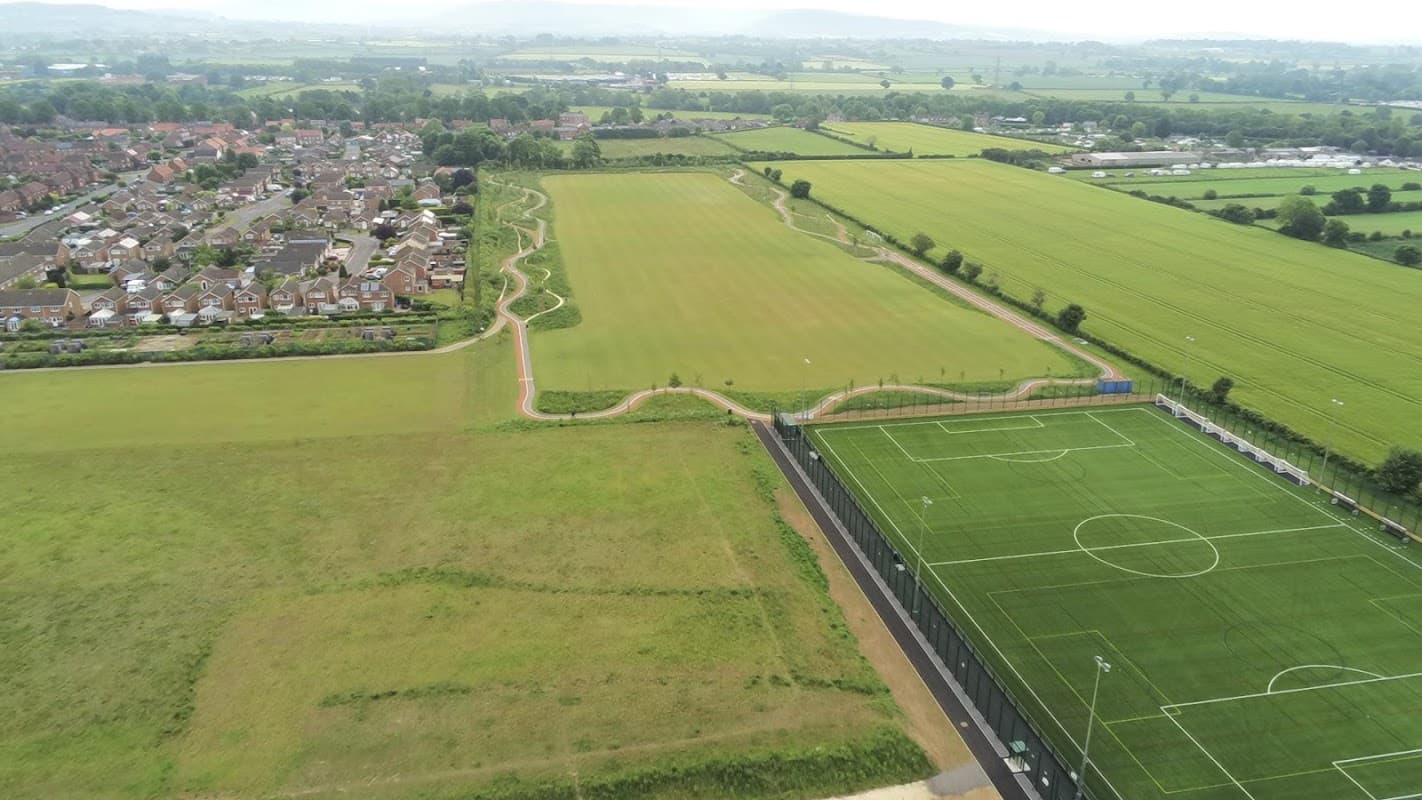 Aerial view of Sowerby Sports Village featuring football pitches, green fields, and nearby residential areas.