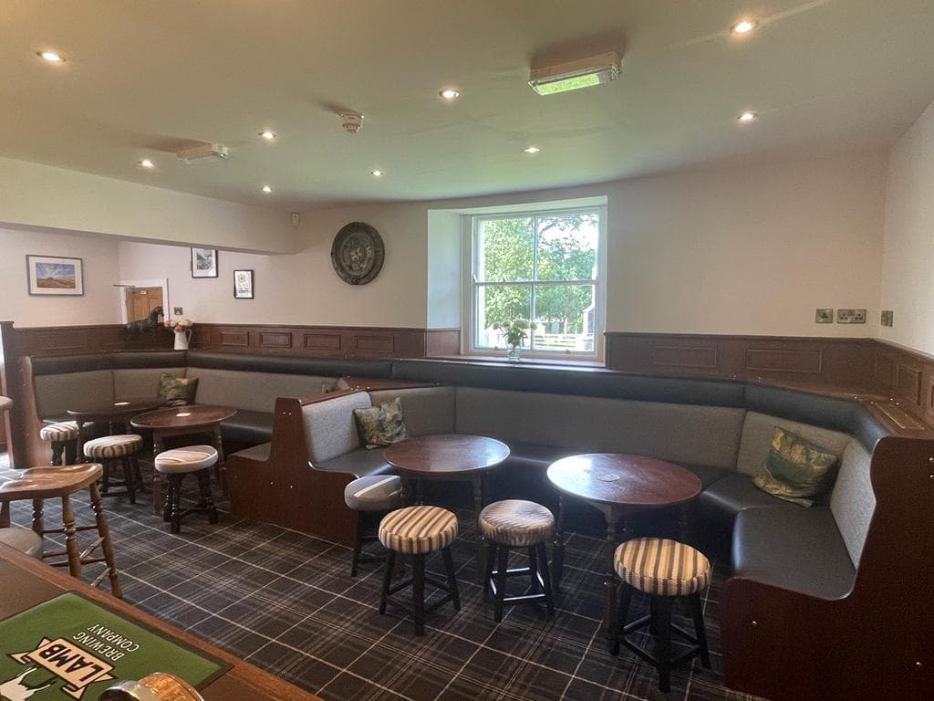 Cozy seating area with wooden tables and chairs, large window, and decorative wall art in a welcoming ambiance.