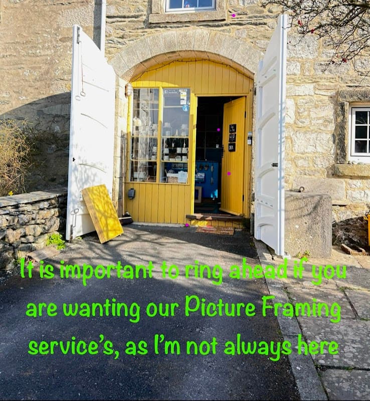 Entrance to The Little Gallery and Framing Studio with yellow doors, stone walls, and a sign about calling ahead.