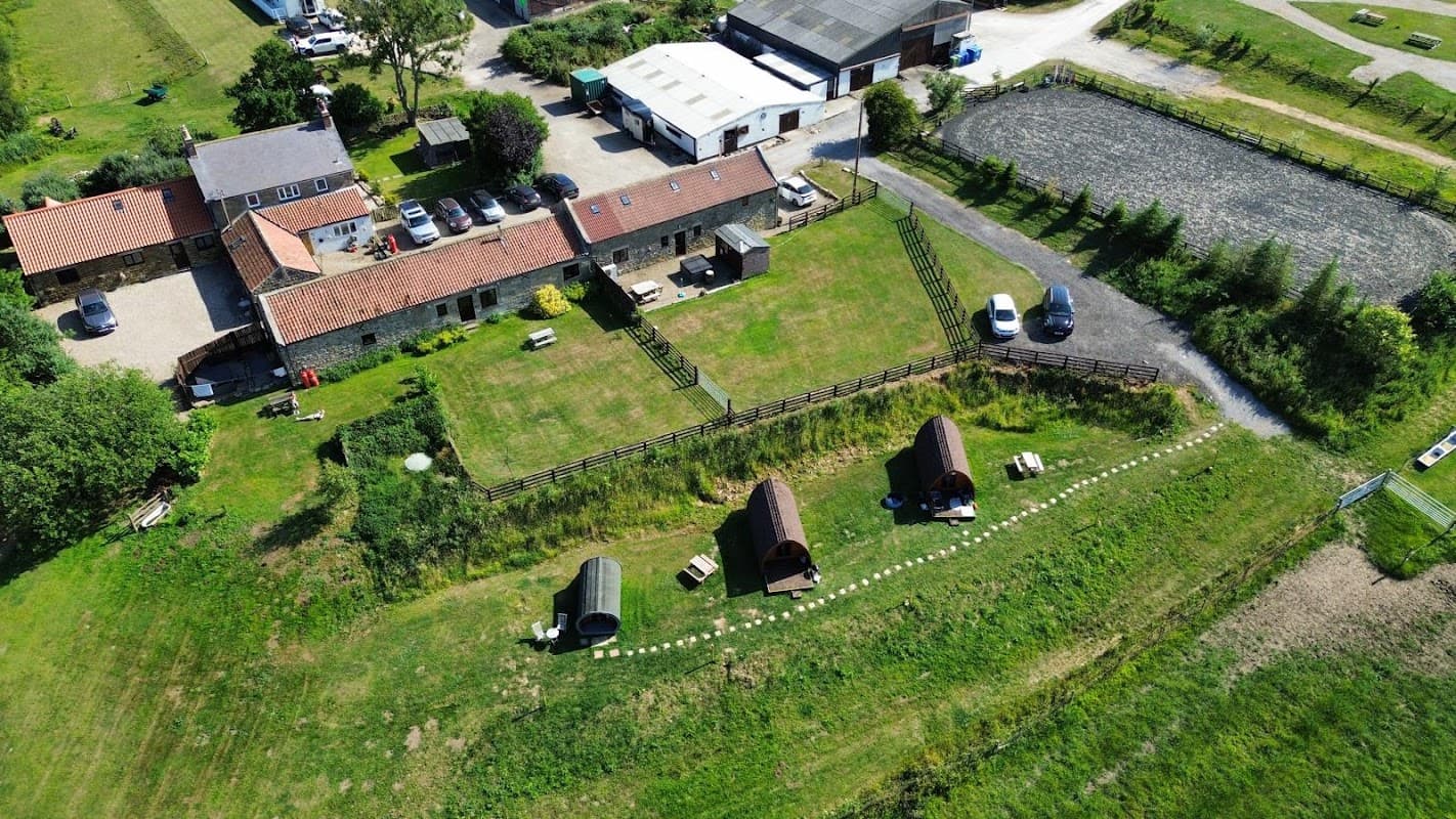 Aerial view of Meeting House Farm Getaways, featuring cabins, grassy areas, and nearby farm buildings in Staintondale.
