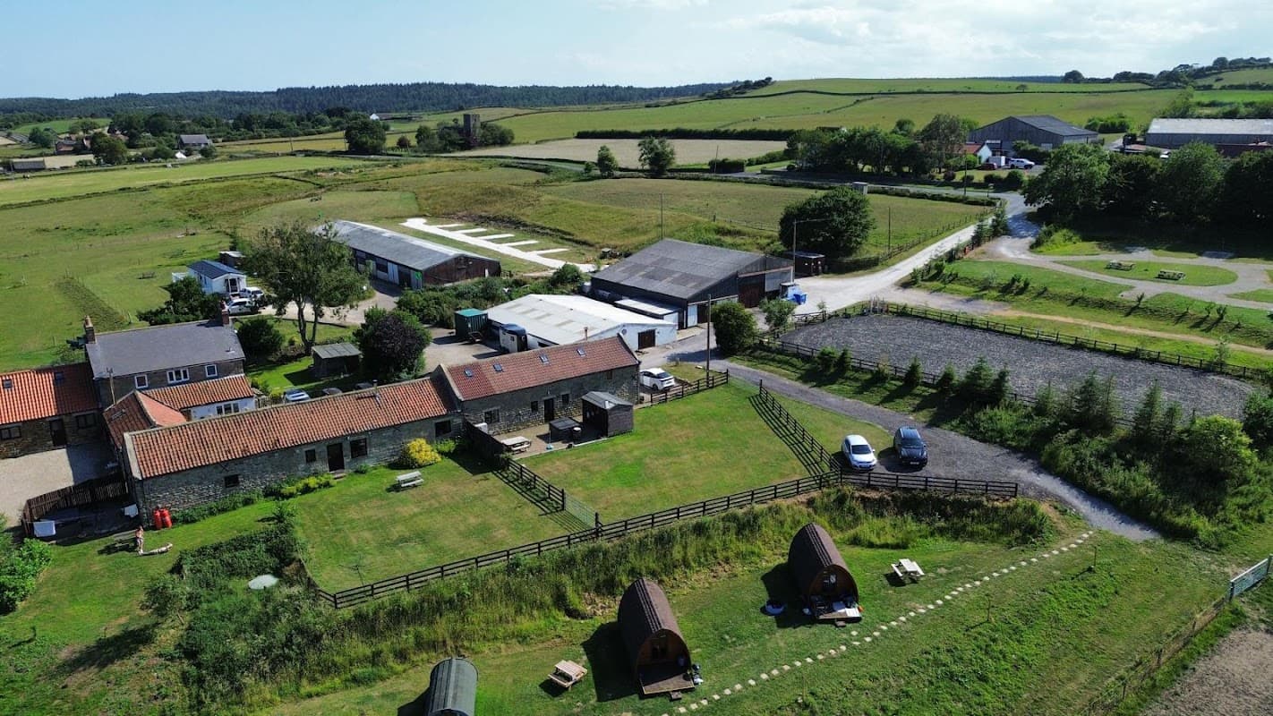 Aerial view of Valley View Campsite with tents, grassy fields, farm buildings, and surrounding hills in Staintondale, Yorkshire.