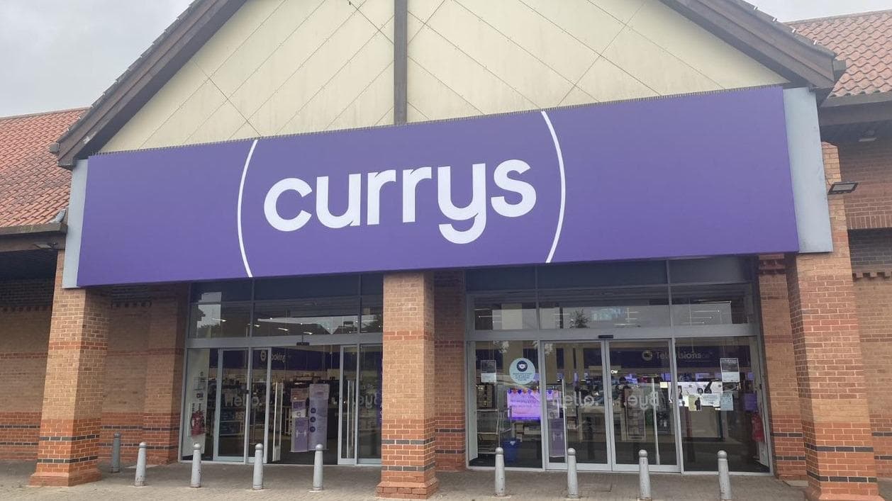 Storefront of Currys in Starbeck, Yorkshire, featuring a large purple sign and brick architecture.