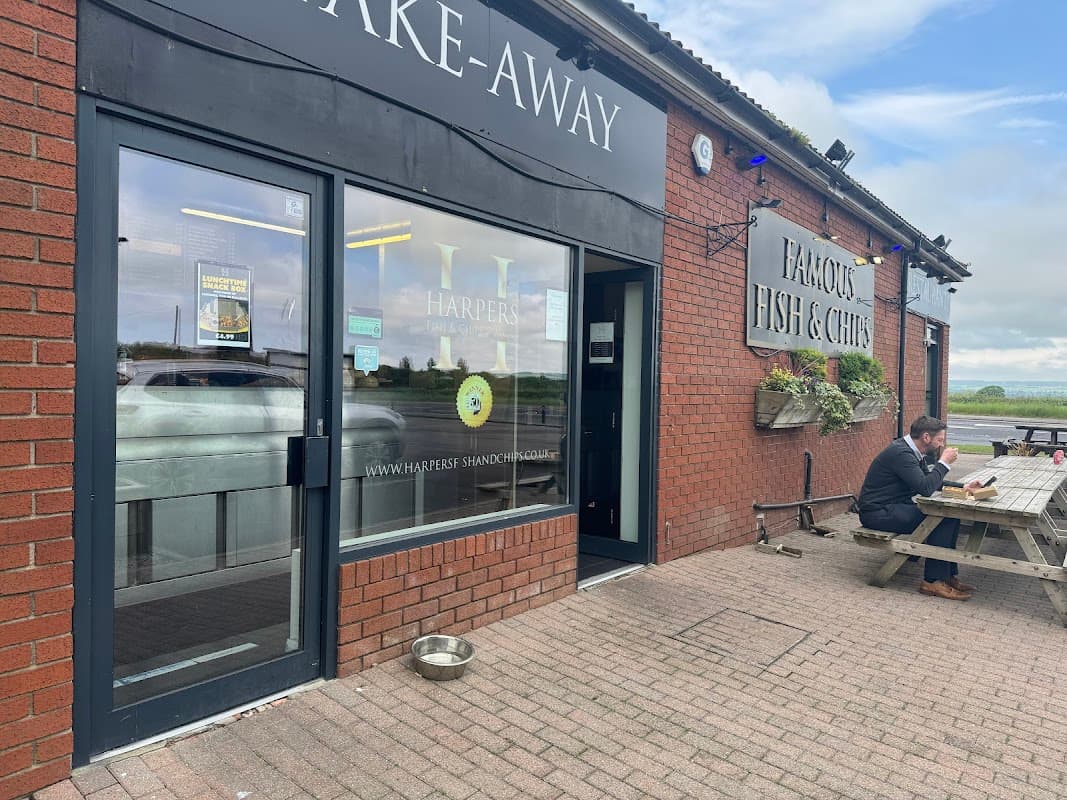 Exterior of Harpers of Staxton restaurant featuring a take-away entrance, outdoor seating, and a customer at a table.