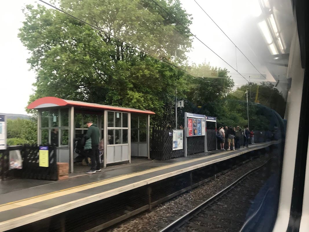 Platform at Steeton & Silsden station with waiting passengers, shelter, and greenery in the background.