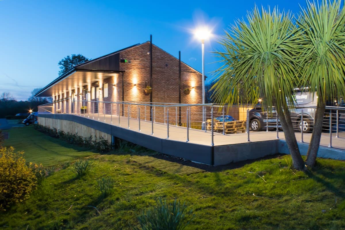 Modern building with warm lights, surrounded by greenery and palm-like plants, at dusk in York Naburn Lock Caravan Park.