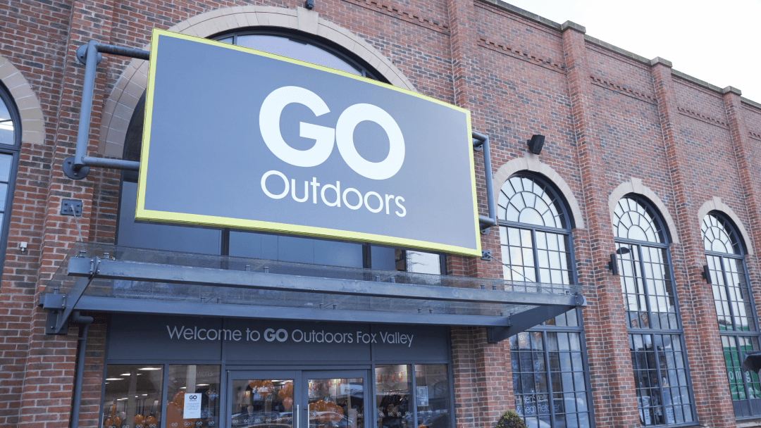 Large "GO Outdoors" sign on a brick building with arched windows, welcoming customers to the sports shop.