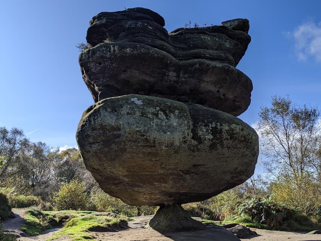 Unique balancing rock formation surrounded by greenery and blue sky at Brimham Rocks, Summerbridge, Yorkshire.