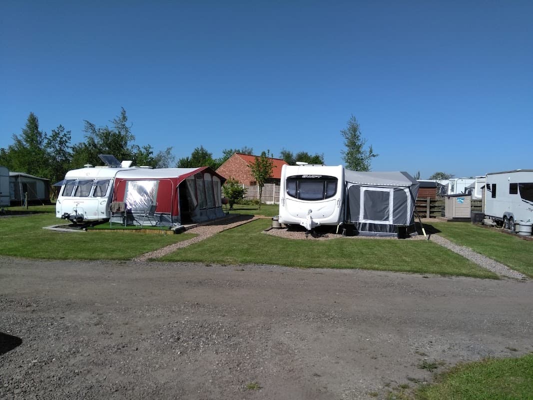 Caravans set on a grassy area with trees and blue sky at Hundred Oaks Caravan Park, Sutton upon Derwent.