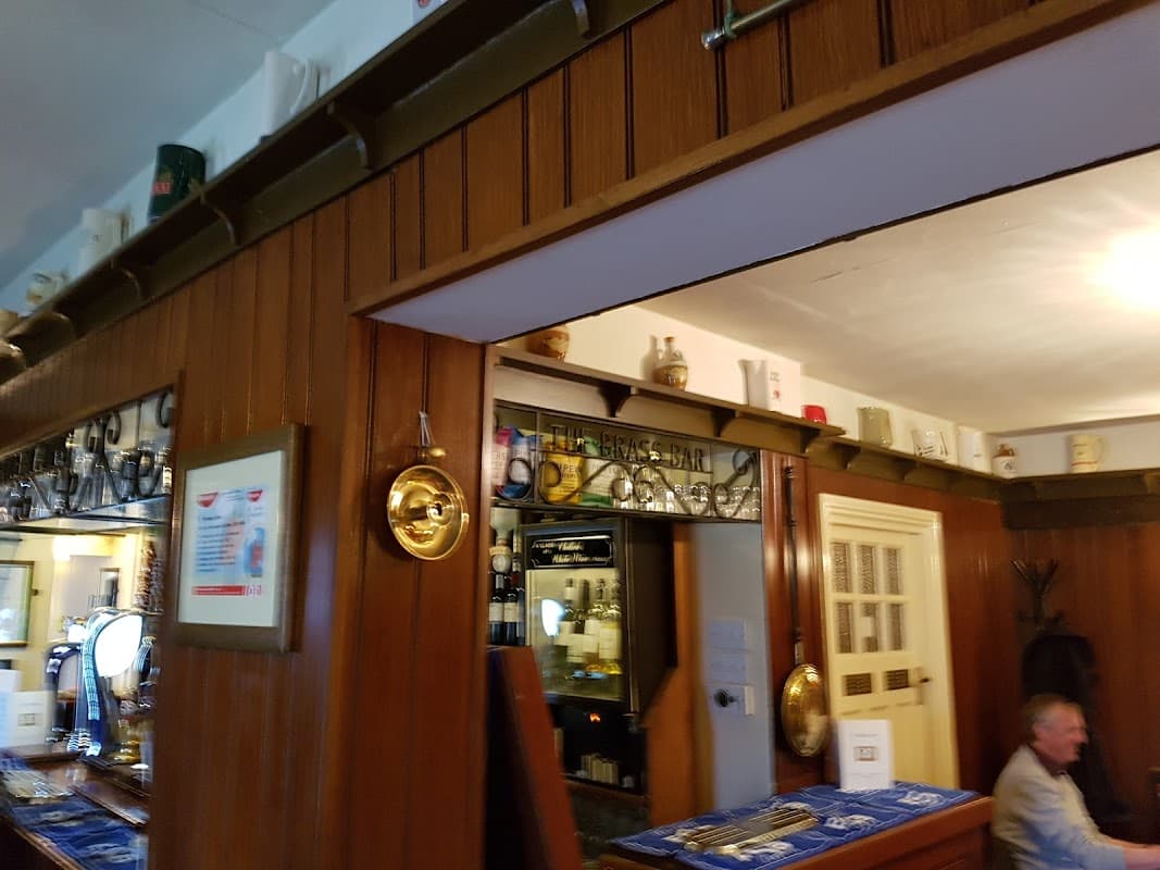 Wood-paneled interior of St Vincent Arms restaurant, featuring a bar area and decorative plates on the ledge.